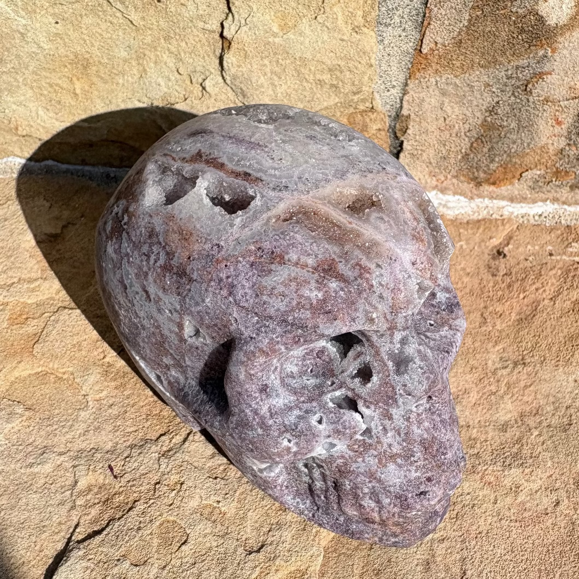 Decorative druzy skull with holes on a textured stone surface
